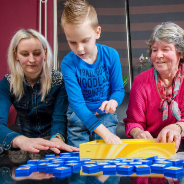 Twee volwassenen spelen een leesspel met een kind